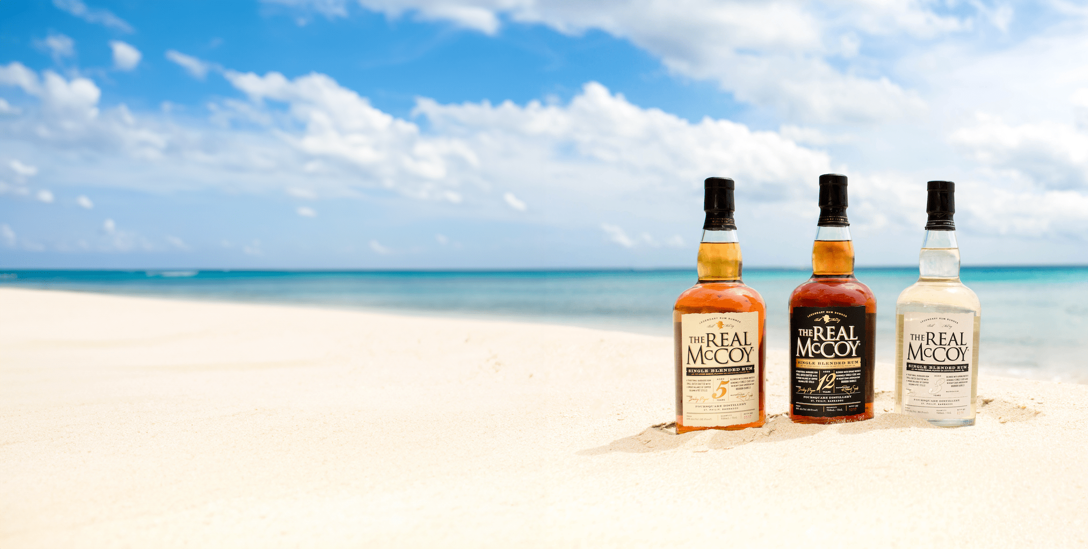 Bottles of Real McCoy 3, 5 & 12 Year Aged Rum in the Sand on a Beach in Barbados