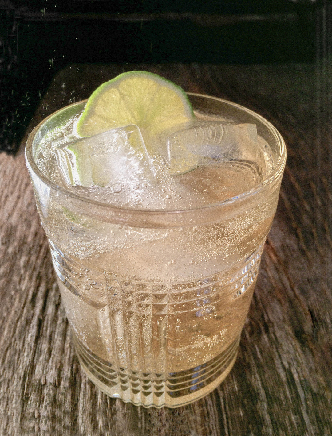 Photo of a real mccoy rum and ginger beer mule in a rocks glass sat on a rustic wood table.