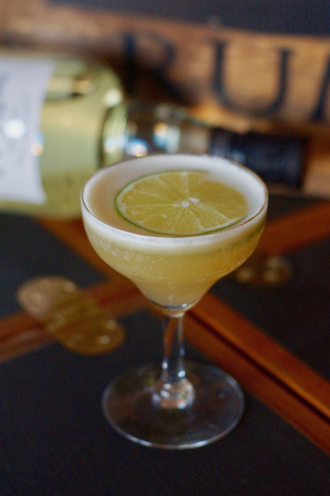 Photo of a daiquiri with a lime wheel floating on top and a bottle of Real McCoy 3 year aged rum in the background.