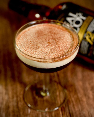 Image of The Velvet Curtain, a real mccoy 12 year aged cocktail similar to an espresso martini in a coupe glass with a beautiful foamy head and cocoa sprinkled on top.